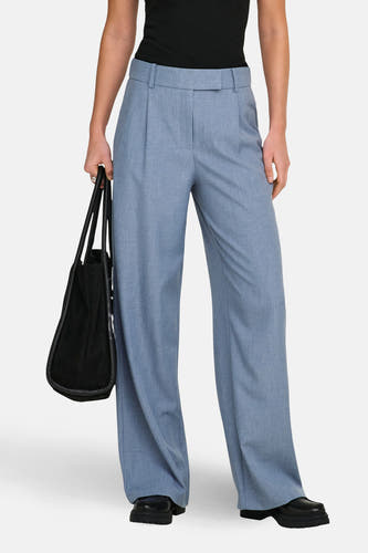 Pantalon de costume bleu ONLY, avec des jambes larges et porté avec un T-shirt noir et une sacoche en cuir.