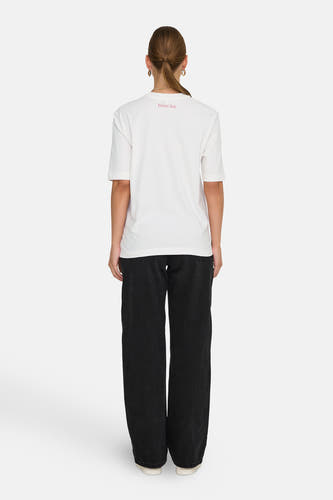 T-shirt blanc à manches courtes de ONLY®, avec détail 'Street Art' sur l'arrière et associé à des jeans noirs.