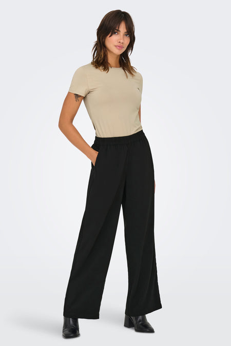 Pantalon noir d'ONLY, avec des jambes larges et une ceinture élastique, associé à un T-shirt beige et des bottines noires.