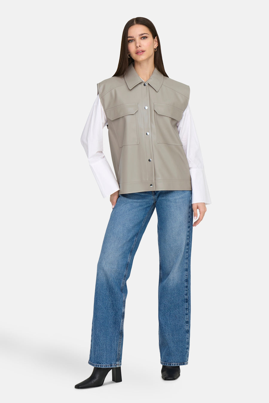 Manteau de cuir beige ONLY®, porté avec un chemisier blanc et des jeans bleus.