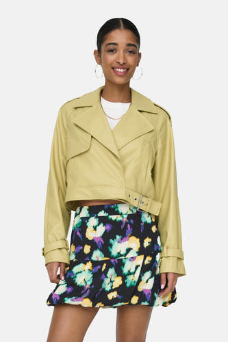 Manteau de cuir jaune d'ONLY, avec des manches longues, porté avec une robe à fleurs et des baskets blanches.