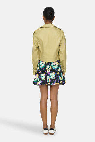 Manteau de cuir noir d'ONLY, avec un imprimé crocodile et porté avec une robe à fleurs.
