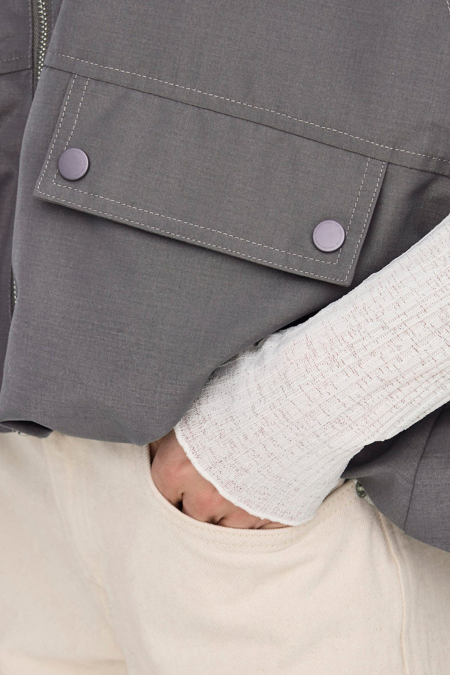 Gilet gris ONLY, avec des poches et une manche blanche côtelée, en gros plan.