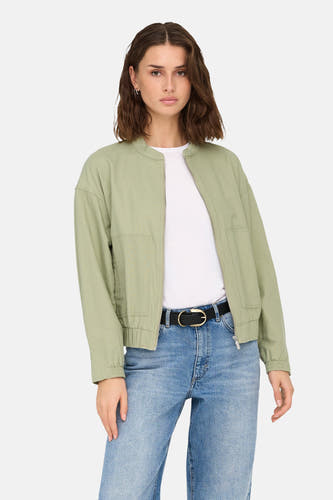 Veste verte de ONLY, portée sur un T-shirt blanc et des jeans bleus avec une ceinture noire.