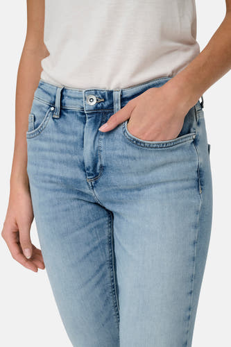 Jean skinny bleu clair en denim ONLY, avec une main dans la poche et un haut léger.