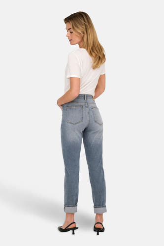 Jean mom en denim bleu mid de ONLY, avec des poches rabattues et associé à un t-shirt blanc et des baskets noires.