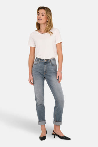 Jean mom bleu moyen d'ONLY, associé à un T-shirt blanc et des sandales glissantes noires.