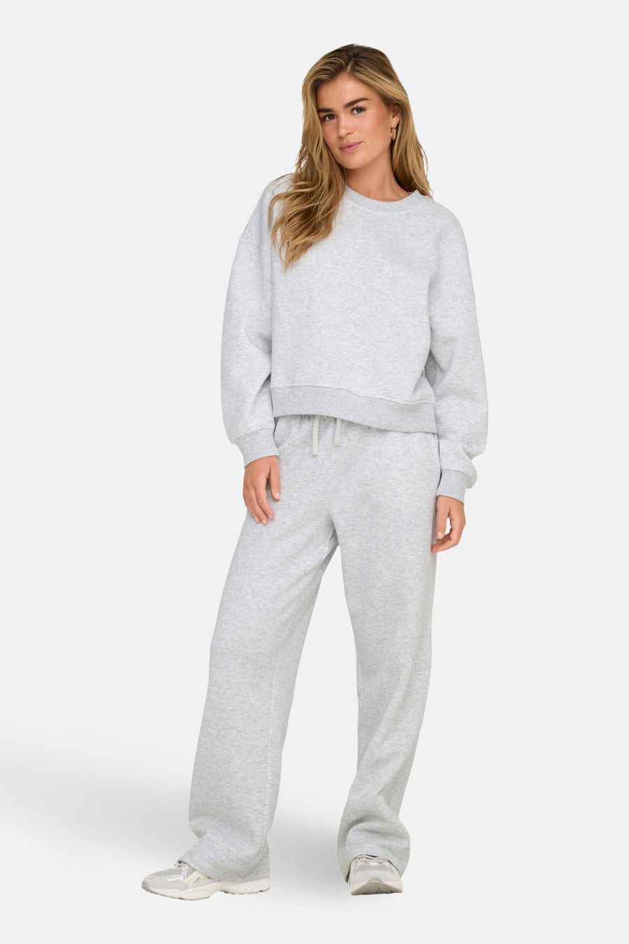 Vrouw in grijze joggingbroek en sweater.