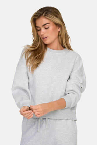 Pull-over gris ONLY, avec col rond, coupe décontractée et longues manches, porté avec un short de jogging coordonné.