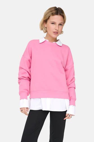 Pull-over rose ONLY, porté sur une chemise blanche et associé à un pantalon noir.