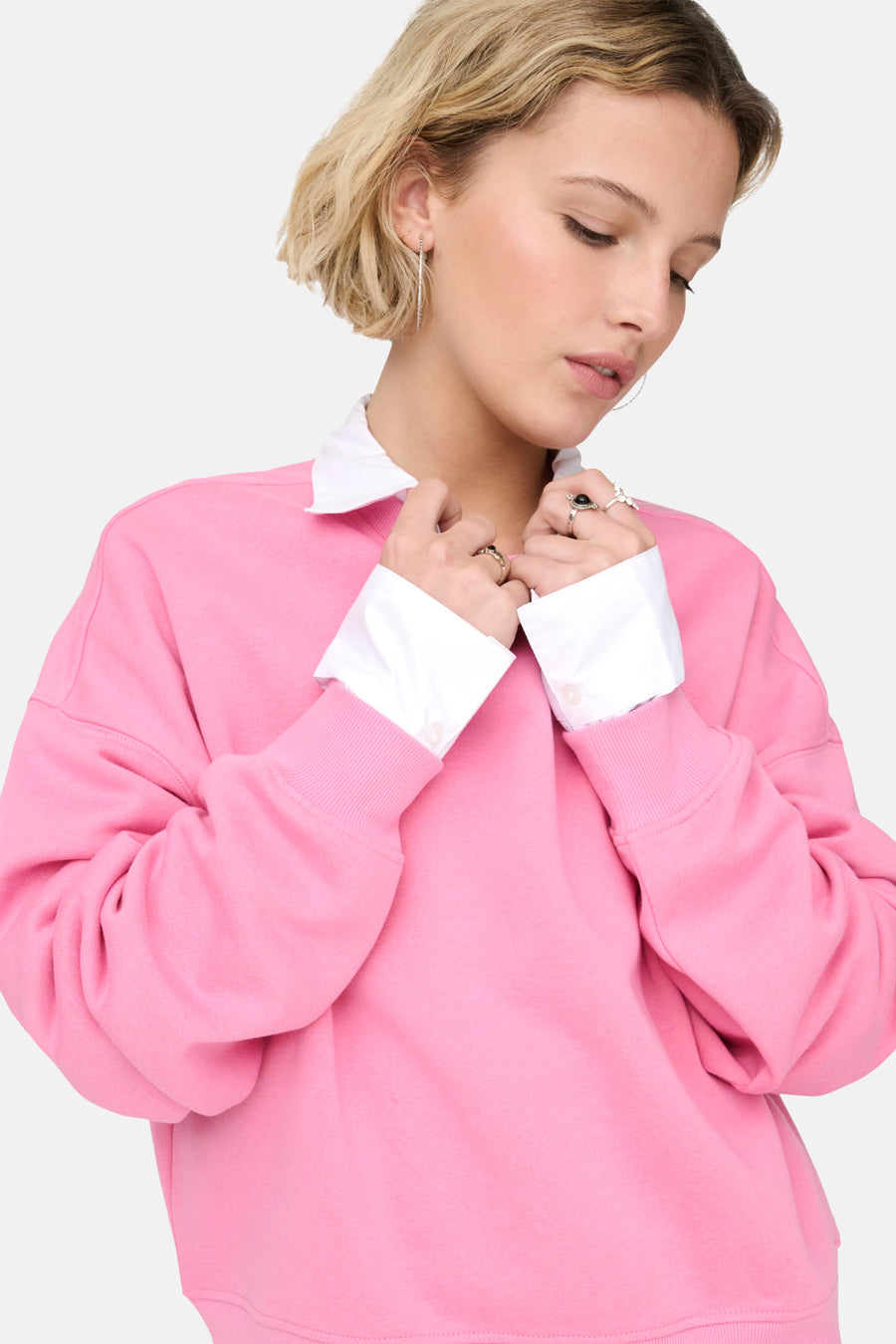 Vrouw met roze sweater en witte blouse.