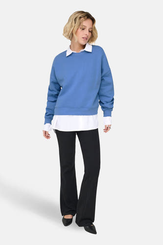 Blauwe sweater van ONLY, gedragen over een wit overhemd met zwarte broek en schoenen.
