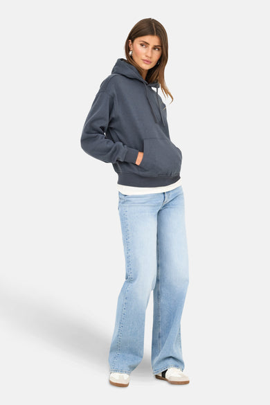 Pull-over bleu avec capuche ONLY, porté avec des jeans larges et des baskets blanches.
