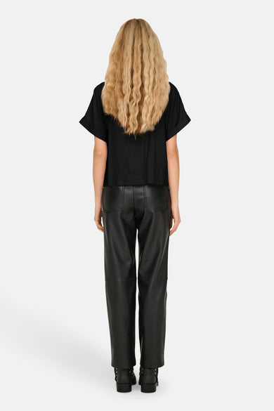 Chemise noire à manches courtes de ONLY, vue de dos avec des cheveux blonds bouclés et un pantalon en cuir.