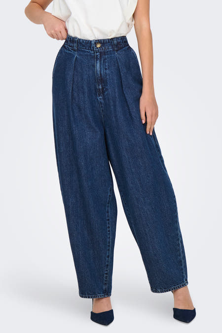 Jean bleu marine, large de ONLY, avec une ceinture élastique et porté avec un haut blanc et des baskets.