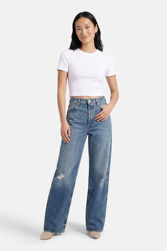 Wit T-shirt met korte mouwen van ONLY®, gedragen met wijde jeans en beige schoenen.
