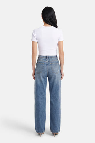T-shirt blanc à manches courtes ONLY, avec un design uni, porté avec un jean bleu et des talons.