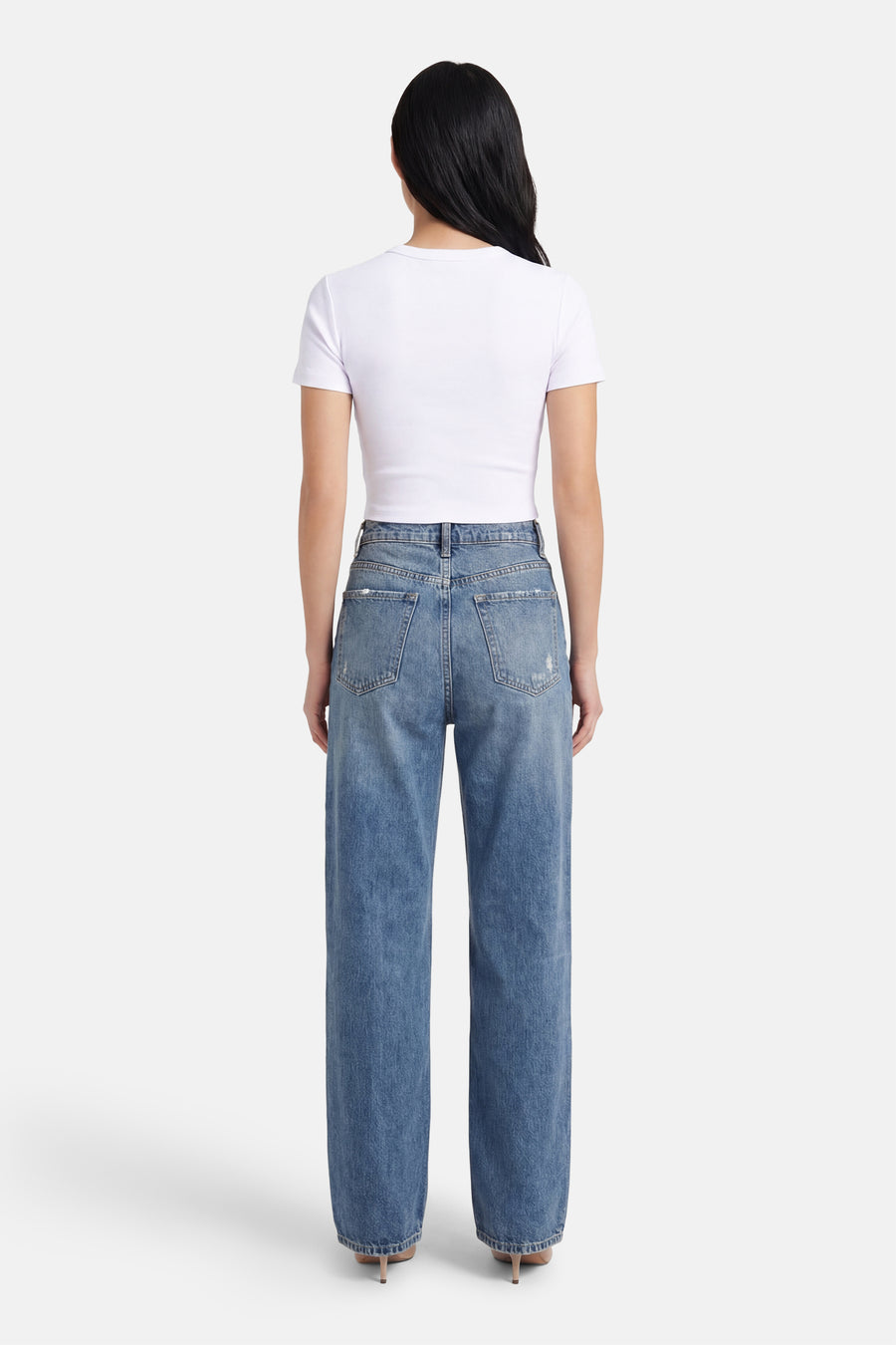 T-shirt blanc à manches courtes ONLY, avec un design uni, porté avec un jean bleu et des talons.