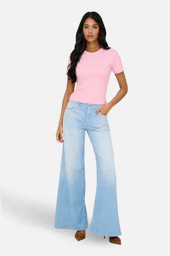 Roze T-shirt met korte mouwen van ONLY®, gedragen met wijde, lichtblauwe jeans en bruine schoenen.