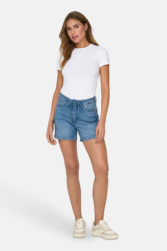 Short blue denim from ONLY, worn with a white shirt and cream-colored sneakers.