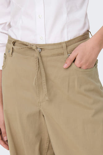 Pantalon beige de ONLY avec une ceinture à la et un main dans la poche.