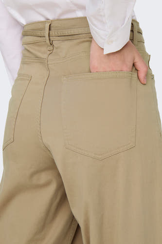 Pantalon beige de ONLY, avec une main dans la poche arrière et des points visibles.