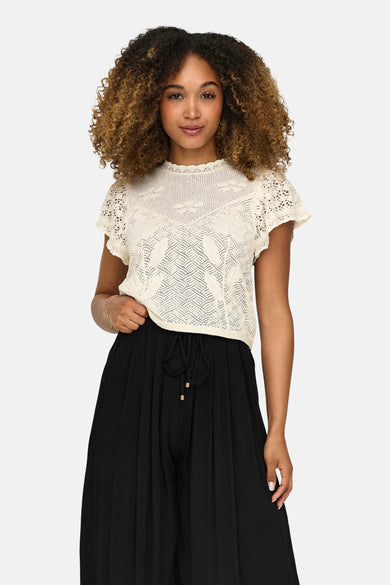 Pull écru ONLY, avec maille ajourée et manches courtes, combiné avec un pantalon noir ample.