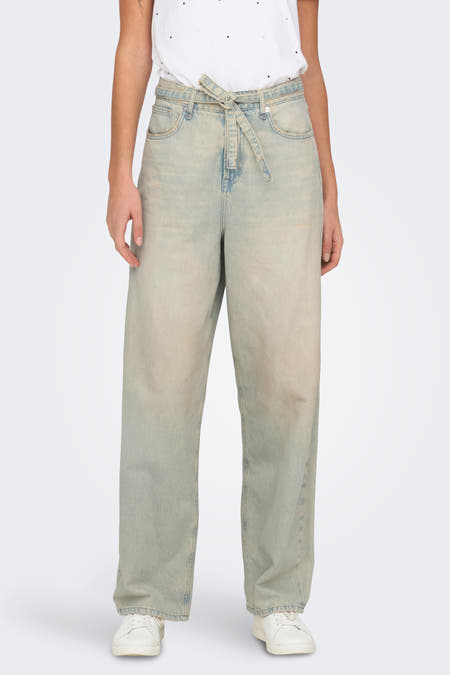 Jean bleu clair large d'ONLY, avec une ceinture à boutons et porté avec un T-shirt blanc et des baskets.