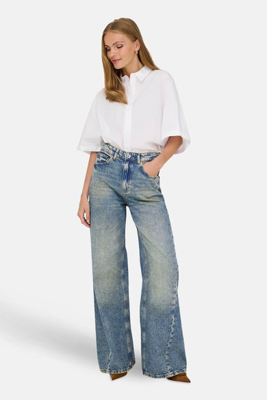 Jean décontracté de denim bleu de JDY, porté avec une chemise blanche et des chaussures marrons.