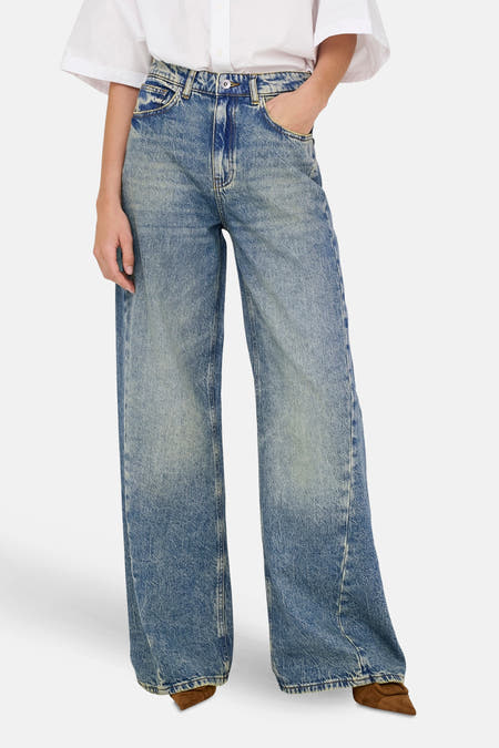 Jean décontracté en denim bleu moyen de JDY, avec des lavages subtils et des baskets brunes.