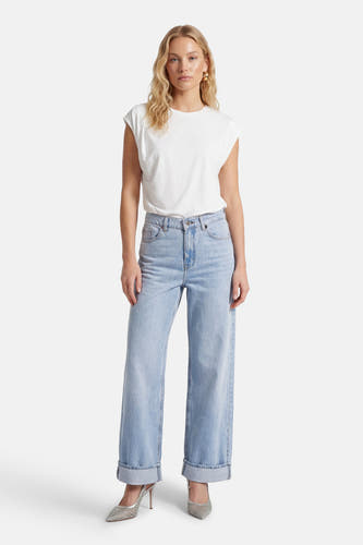 HOPE lichtblauwe denim jeans wide van ONLY, met omgeslagen pijpen en gecombineerd met een wit T-shirt en zilveren pumps.
