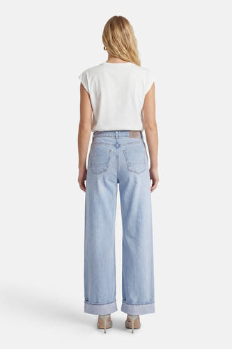 Jean large bleu clair de ONLY, avec ourlet retroussé et porté avec un t-shirt blanc et des chaussures à paillettes.