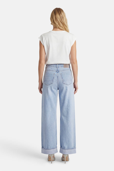 Lichtblauwe wide jeans van ONLY, met opgerolde zoom en gedragen met een wit T-shirt en glitterschoenen.
