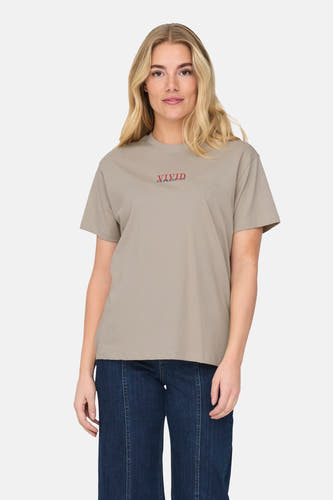 T-shirt beige à manches courtes de ONLY, avec imprimé texte rouge, associé à un pantalon bleu marine.