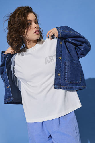 T-shirt blanc à manches courtes d'ONLY, avec un motif à carreaux formant le mot "ART", associé à une veste en cuir et des shortts de lin bleus.