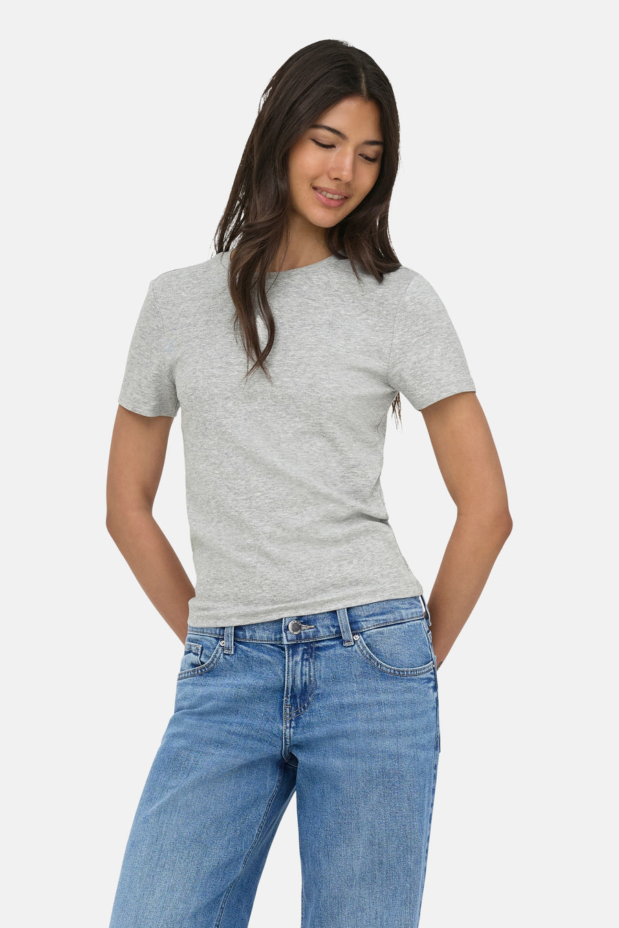 T-shirt gris chiné à manches courtes ONLY®, avec col rond, combiné avec un jean bleu coupe large et des talons blancs.