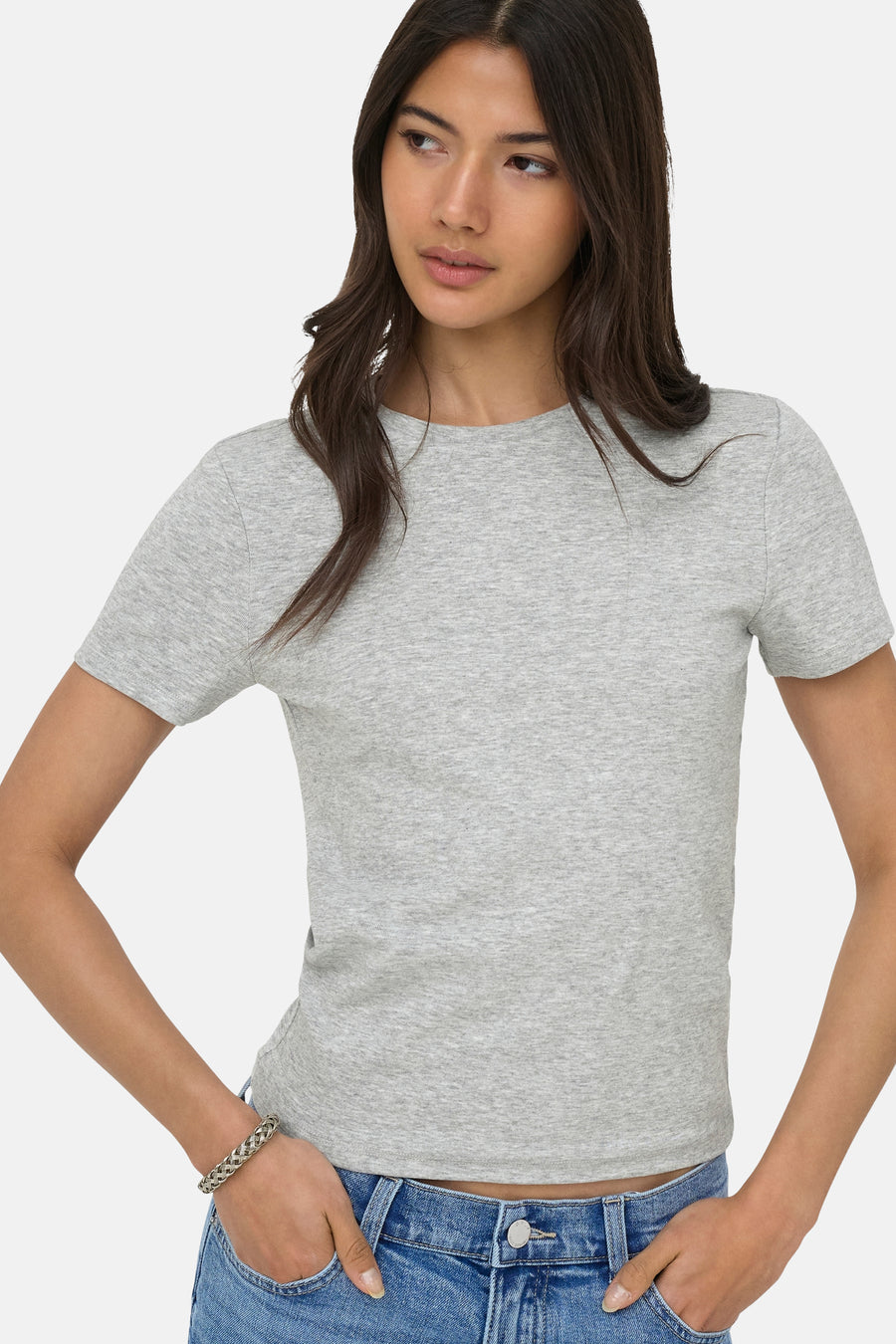 T-shirt chiné gris d'ONLY® à col rond et manches courtes, porté par un mannequin en jean avec un bracelet argenté.