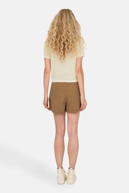 T-shirt écru ONLY, vu sur le dos, avec un détail crocheté et associé à des short bruns et des baskets blanches.