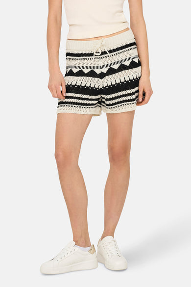 Crème court ONLY, avec un motif tricoté et une ceinture à la taille, porté avec un haut blanc et des baskets blanches.
