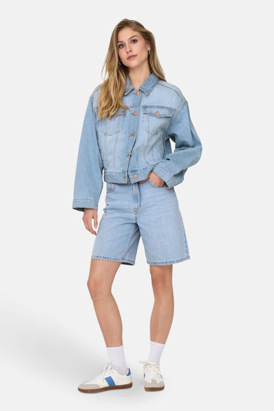 Short en denim bleu clair de ONLY, porté avec un blouson en denim et des baskets blanches.