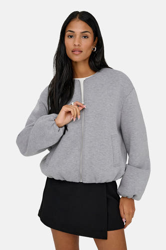 Veste grise ONLY®, à manches longues, portée avec un short noir et des bottes en cuir, vue de dos.