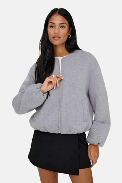 Veste grise ONLY®, à manches longues, portée avec un short noir et des bottes en cuir, vue de dos.