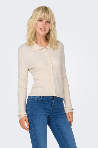 Pull écru tricoté de ONLY, avec des manches longues, porté avec des jeans bleus et des chaussures noires.