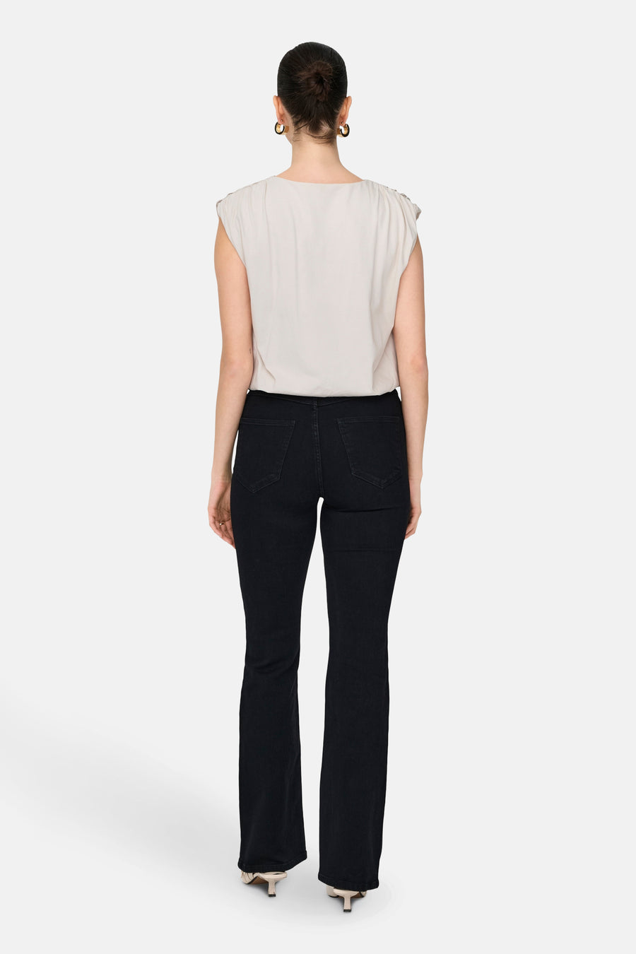 Blouse blanche JDY, vue de derrière, associée à des jeans foncés et des boucles d'oreilles dorées.