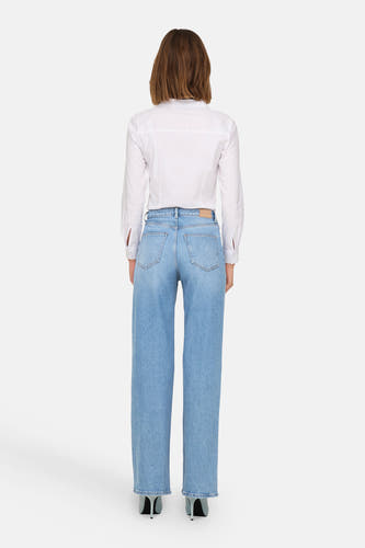 Jean ample bleu clair de ONLY, avec une blouse blanche et des escarpins noirs.