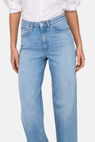 Jean en denim bleu clair évasé de ONLY, avec une blouse blanche.