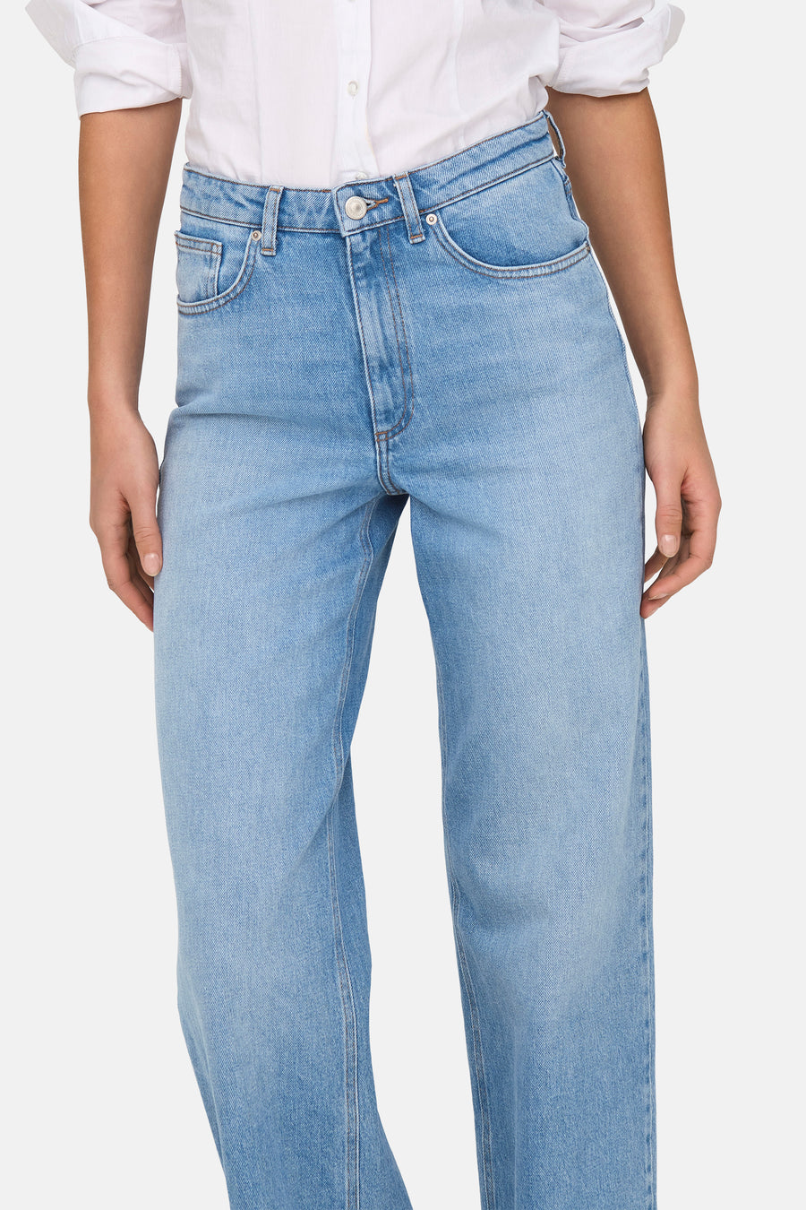 Jean en denim bleu clair évasé de ONLY, avec une blouse blanche.