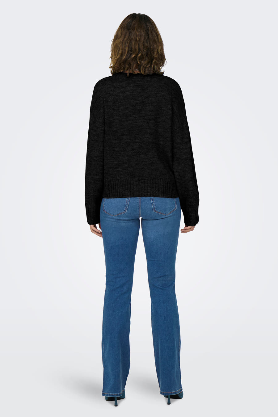 Pull-over noir avec col rond de ONLY, vu de derrière, associé à un pantalon de travail bleu et des escarpins verts.