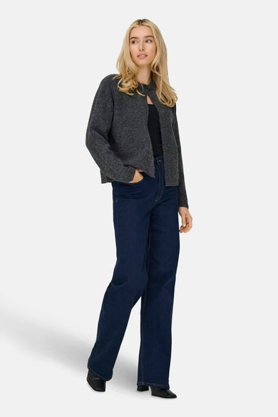 Veste grise d'ONLY, portée sur une chemise noire avec des jeans foncés et des chaussures noires.