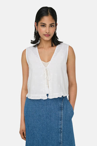Blouse sans manches blanche de ONLY, avec des détails brodés et un bord plié, associée à une jupe bleue.